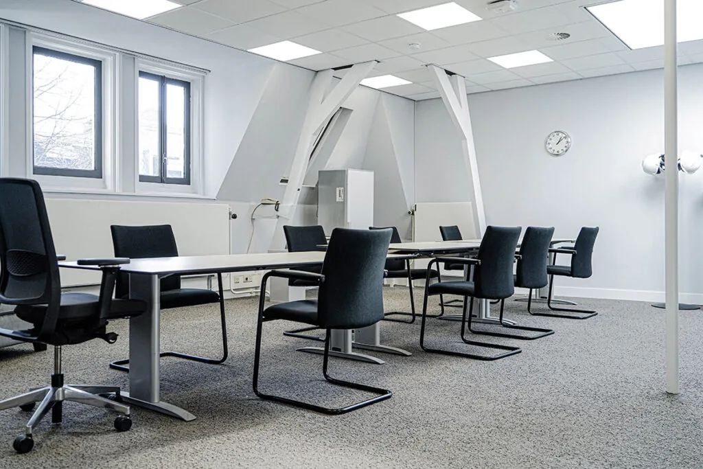 Vergaderruimte aan de Burgemeester van Karnebeeklaan met moderne inrichting, zwarte stoelen en een lang vergadertafel.